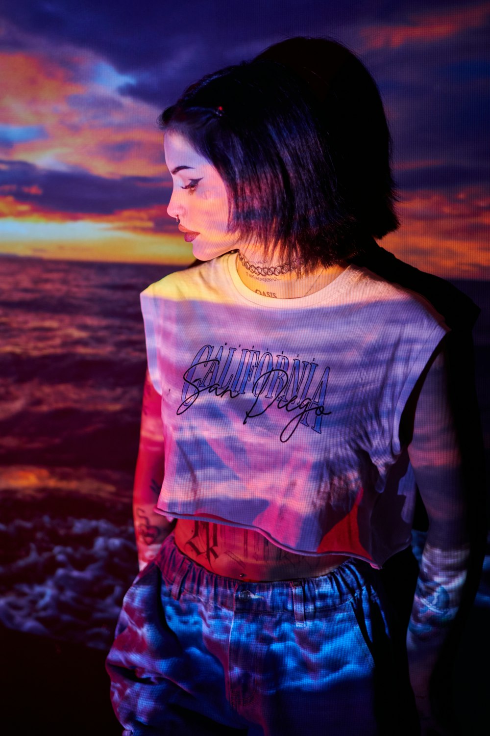 a woman standing in front of the ocean at sunset