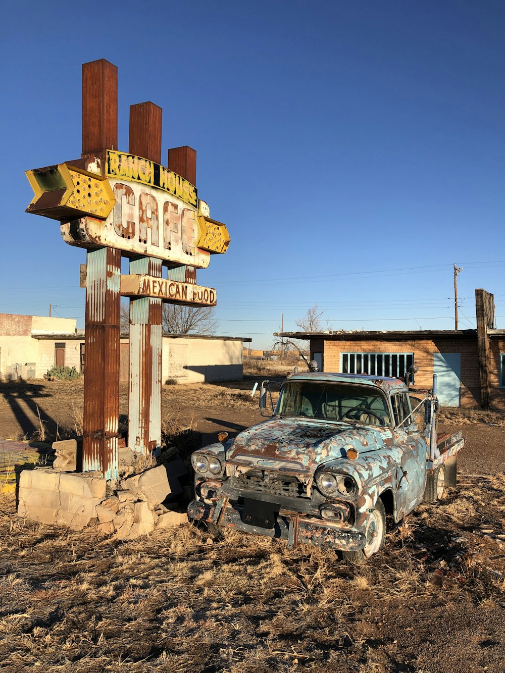 an old car is parked in front of a sign