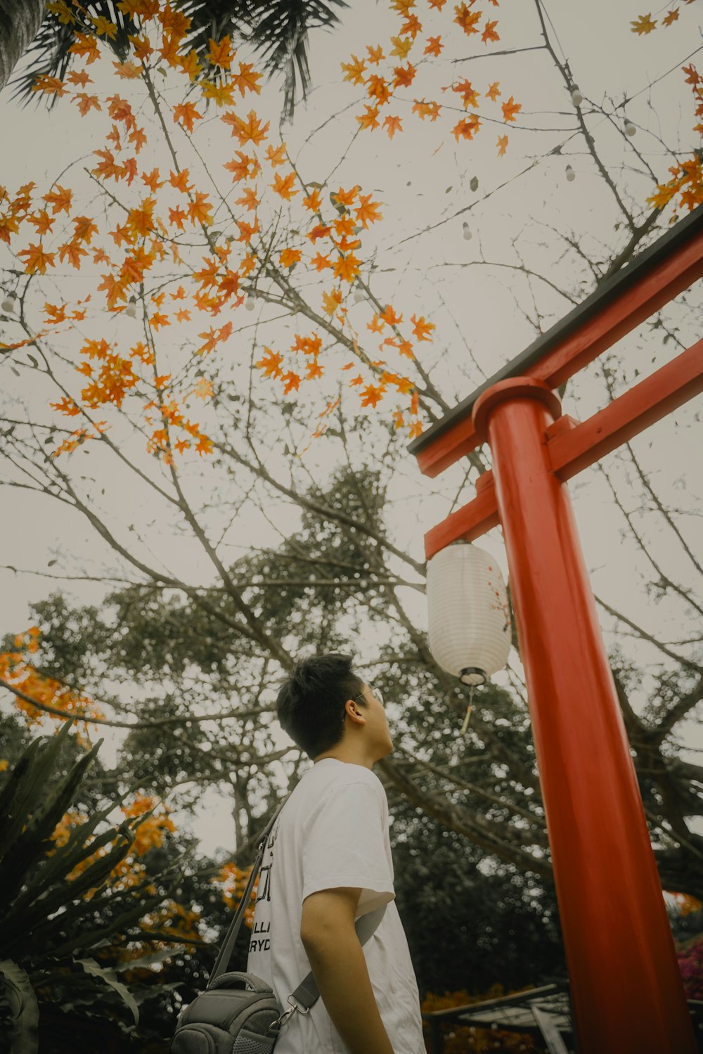 a man in a white shirt is standing under a red pole