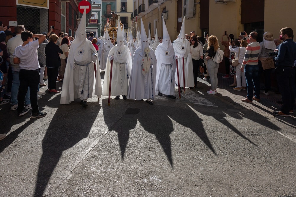 a group of people dressed in white standing in the street