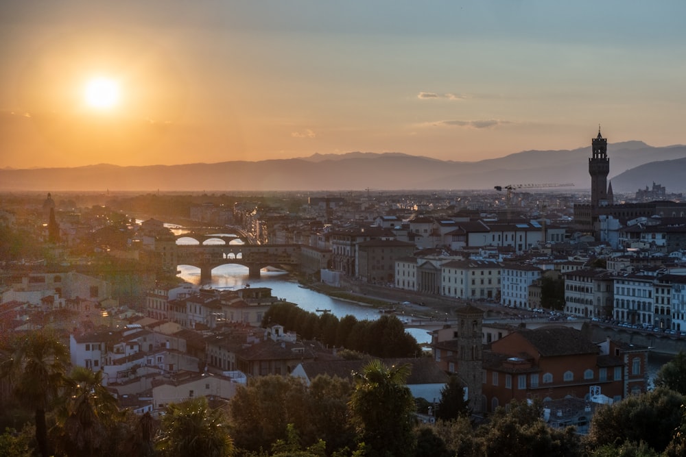 the sun is setting over a city with a river running through it