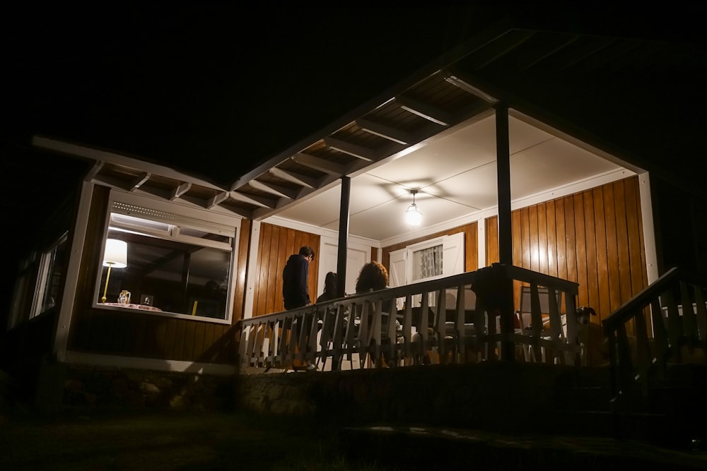 a couple of people standing on a porch at night