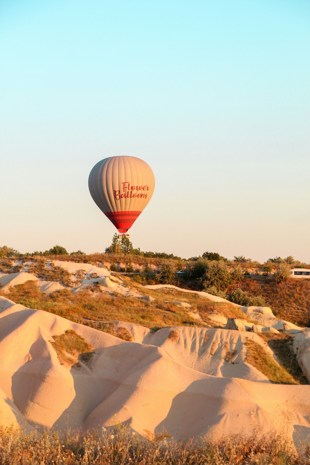 a hot air balloon flying over sand dunes