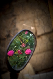 Close-up of a car mirror wrapped in delicate white flowers and green leaves.
