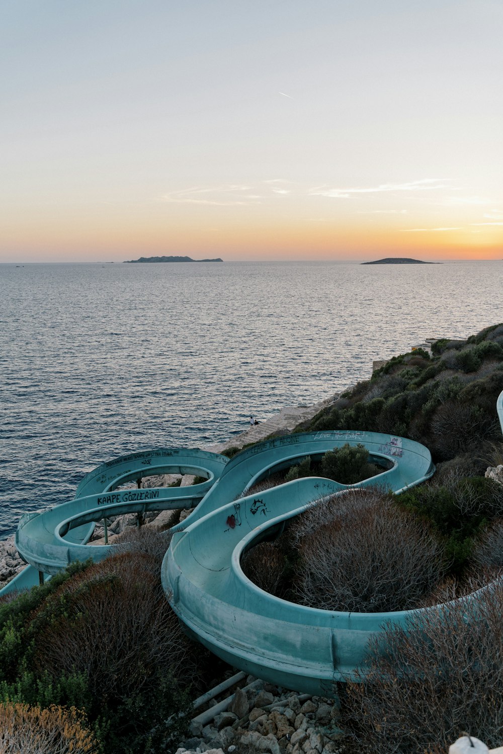 a row of water slides sitting on top of a hill next to the ocean