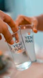 two people holding glasses with water in them