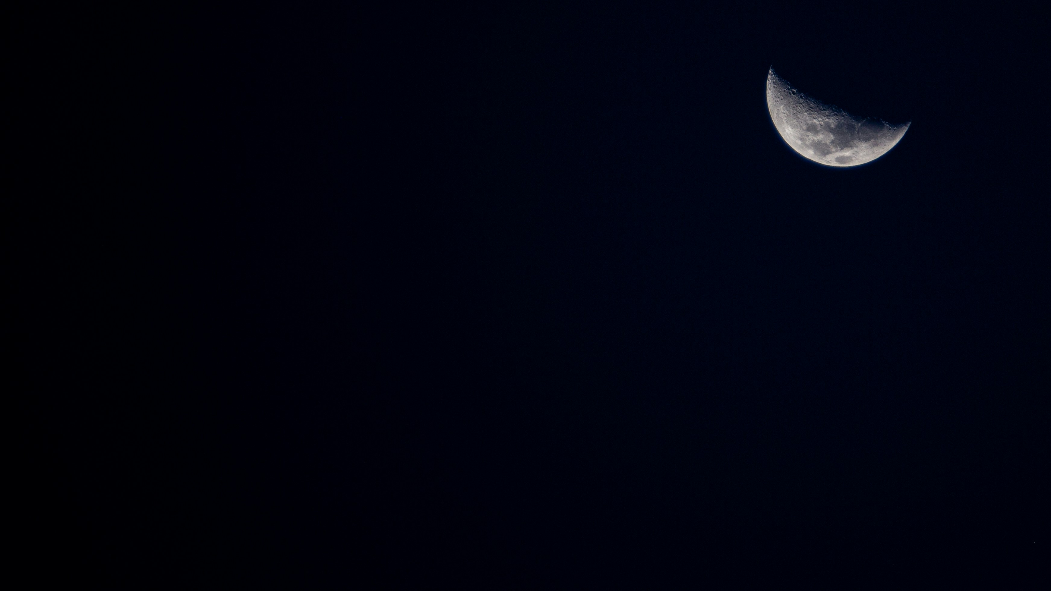 a half moon is seen in the dark sky