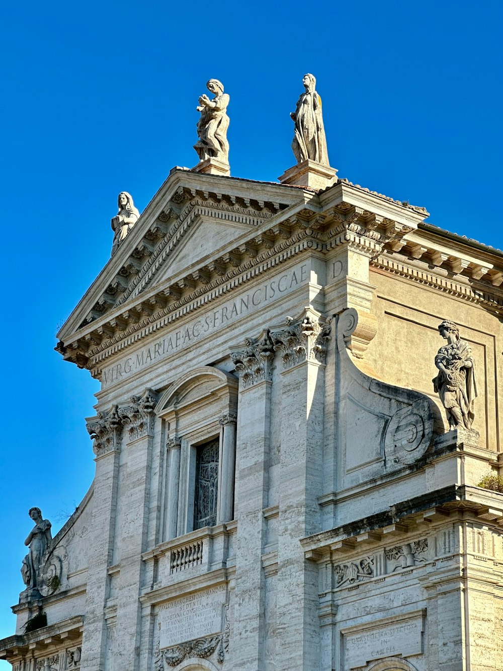 Un edificio alto con estatuas en la parte superior