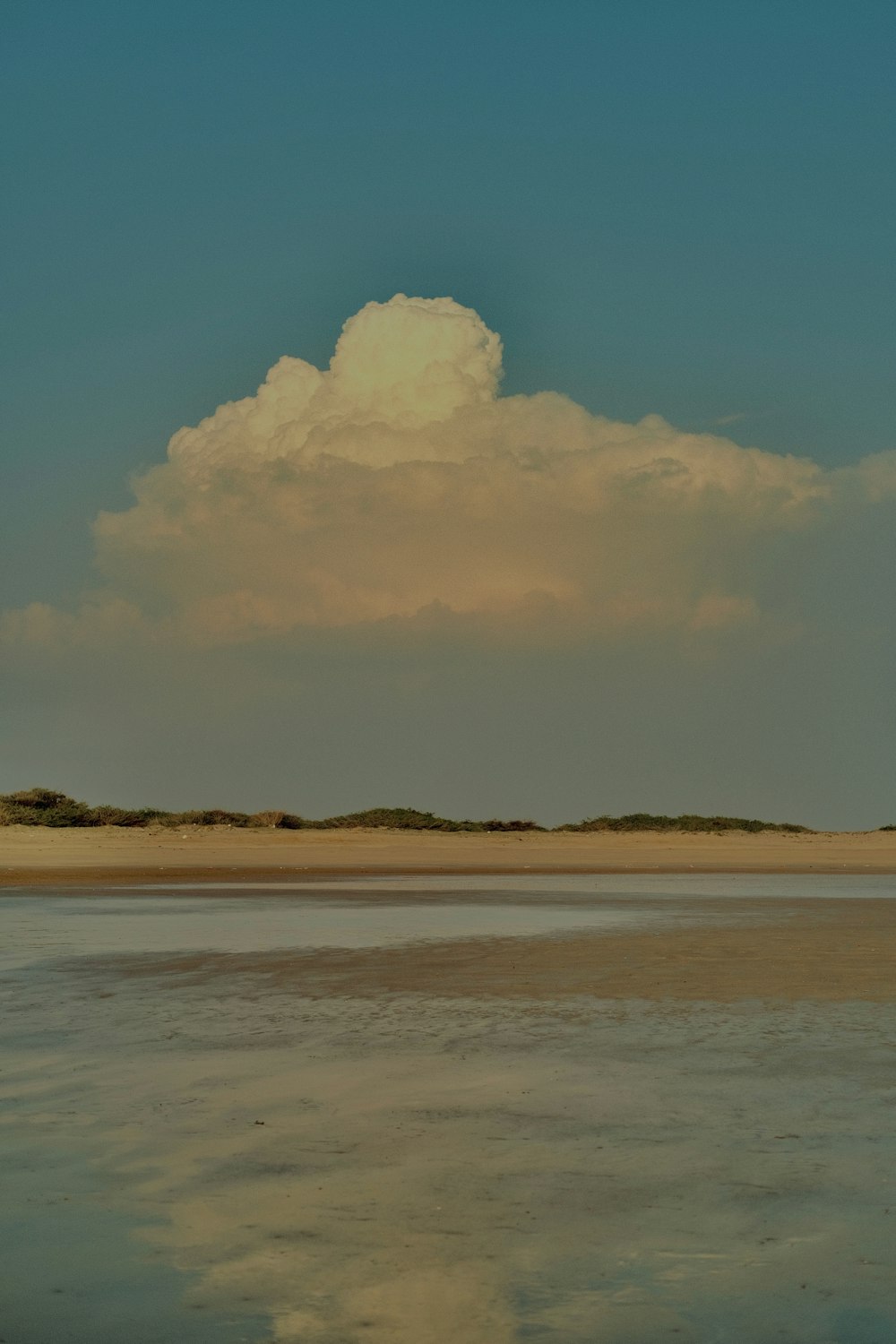 a large cloud is in the sky above a body of water