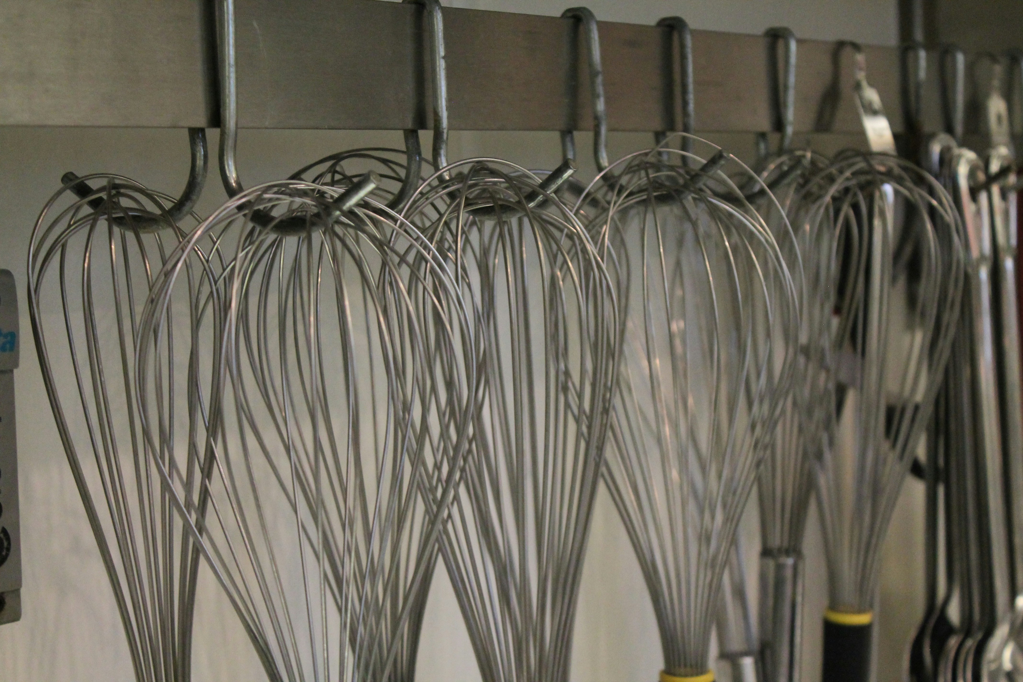 A bunch of whisks hanging on a wall