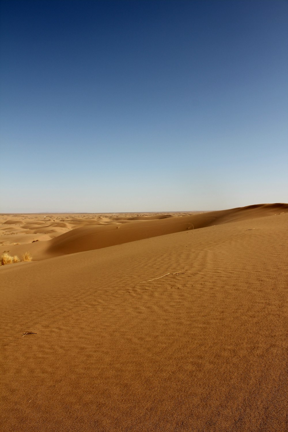 a desert landscape with sand dunes and a blue sky