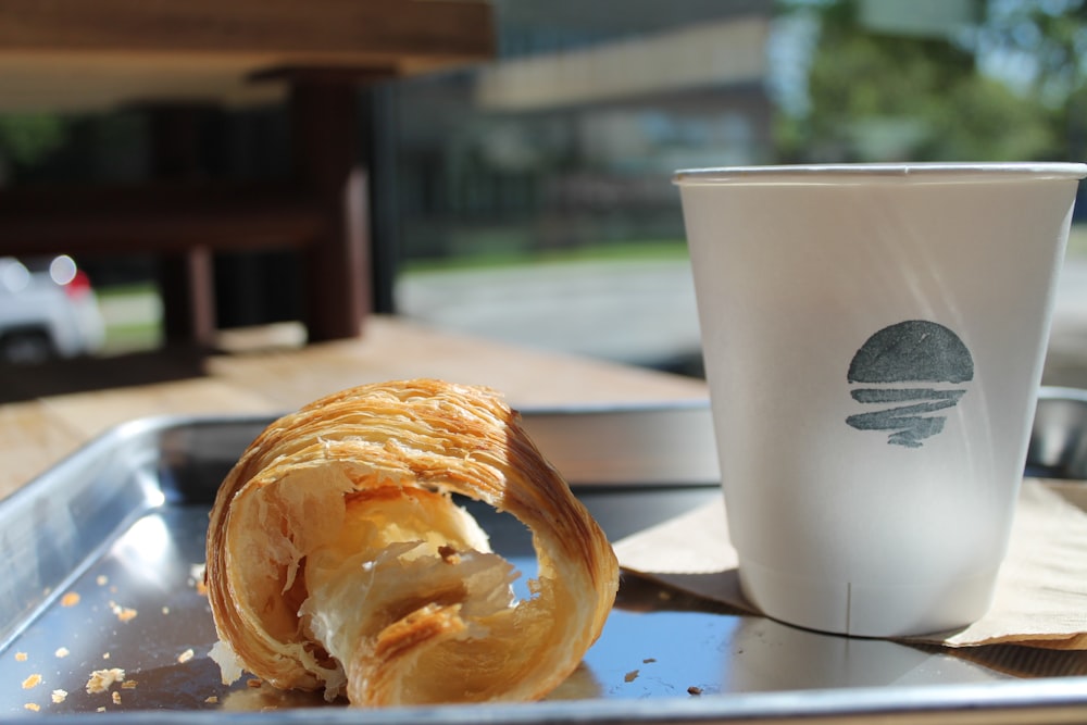 a pastry on a tray next to a cup of coffee