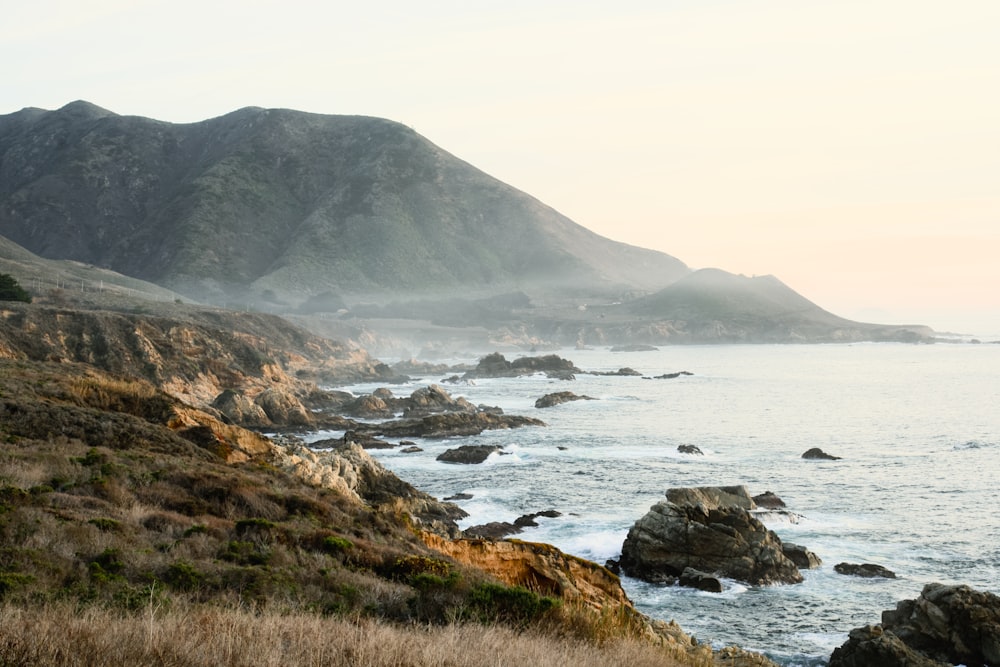 a large body of water sitting next to a lush green hillside