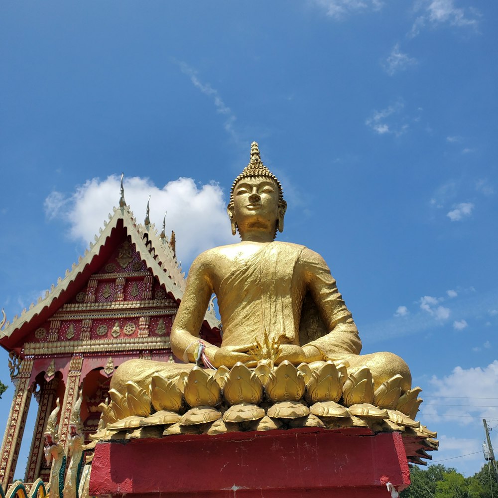 a large golden buddha statue sitting in front of a building