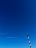 Outdoor cable installation on a utility pole under a clear blue sky.