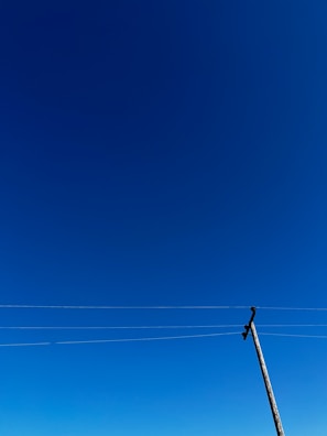 Outdoor cable installation on a utility pole under a clear blue sky.