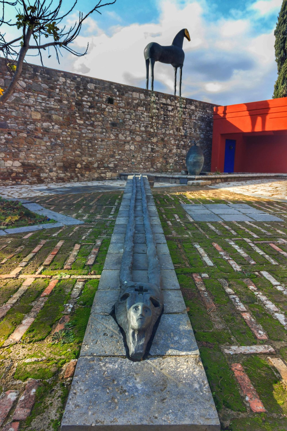 a dog laying on the ground in front of a statue of a horse