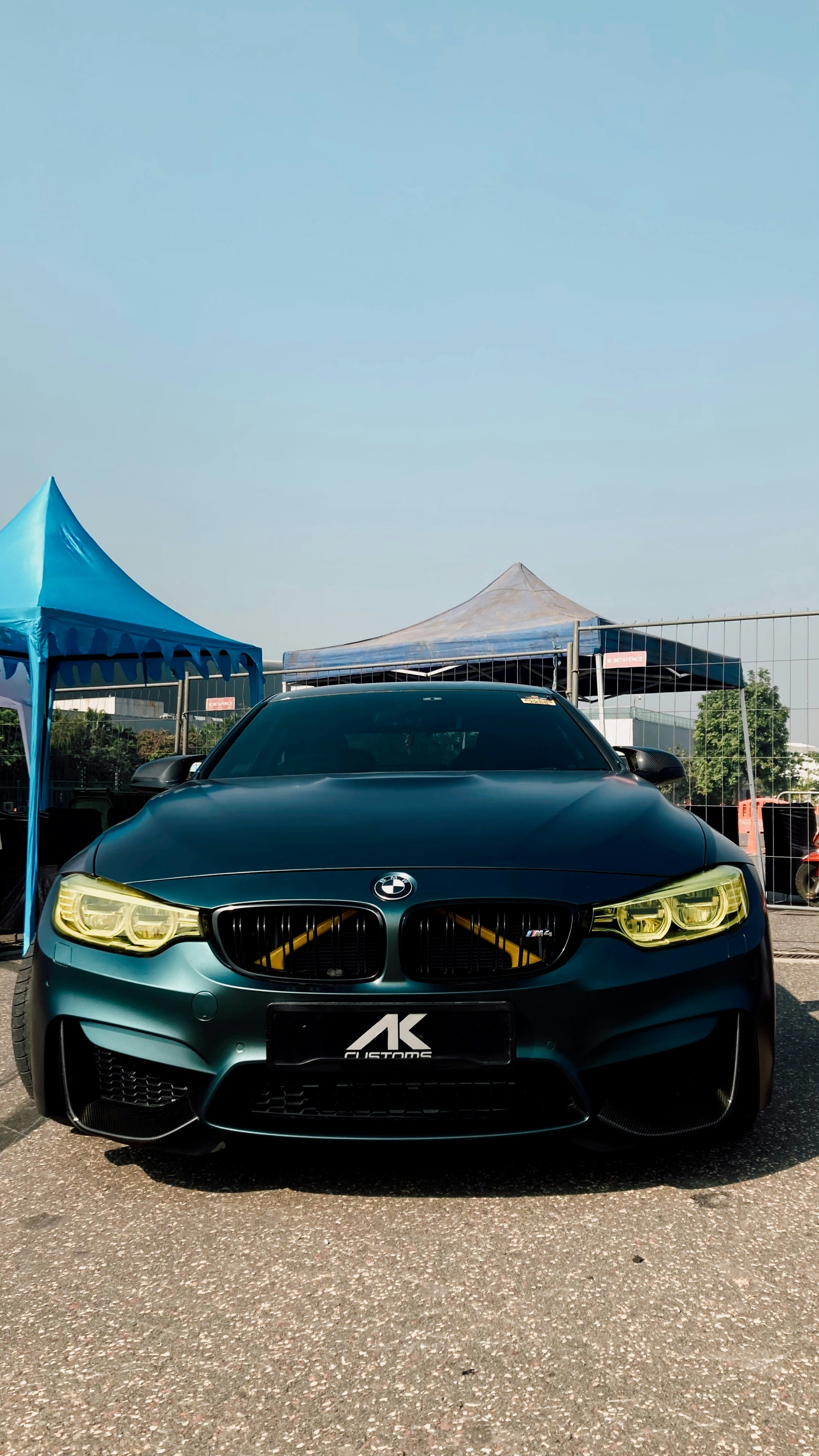 a black car parked in a parking lot next to a blue tent