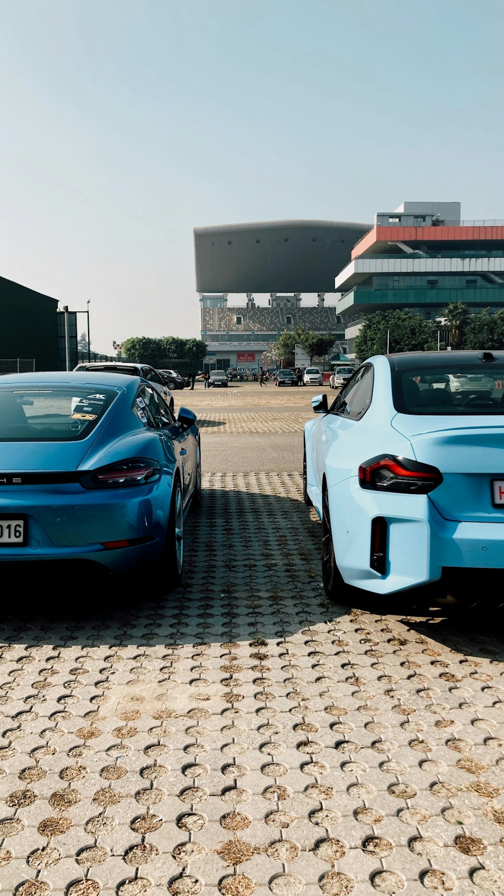 two blue sports cars parked in front of a building