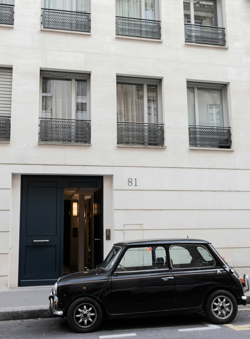 a small black car parked in front of a building