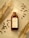 A bottle of cold brew coffee is placed on a surface surrounded by scattered coffee beans and dry wheat stalks. The label on the bottle reads 'COLD BREW BLEND COFFEE' and contains 100 ML. The scene is set in warm lighting, creating a cozy and inviting ambiance.