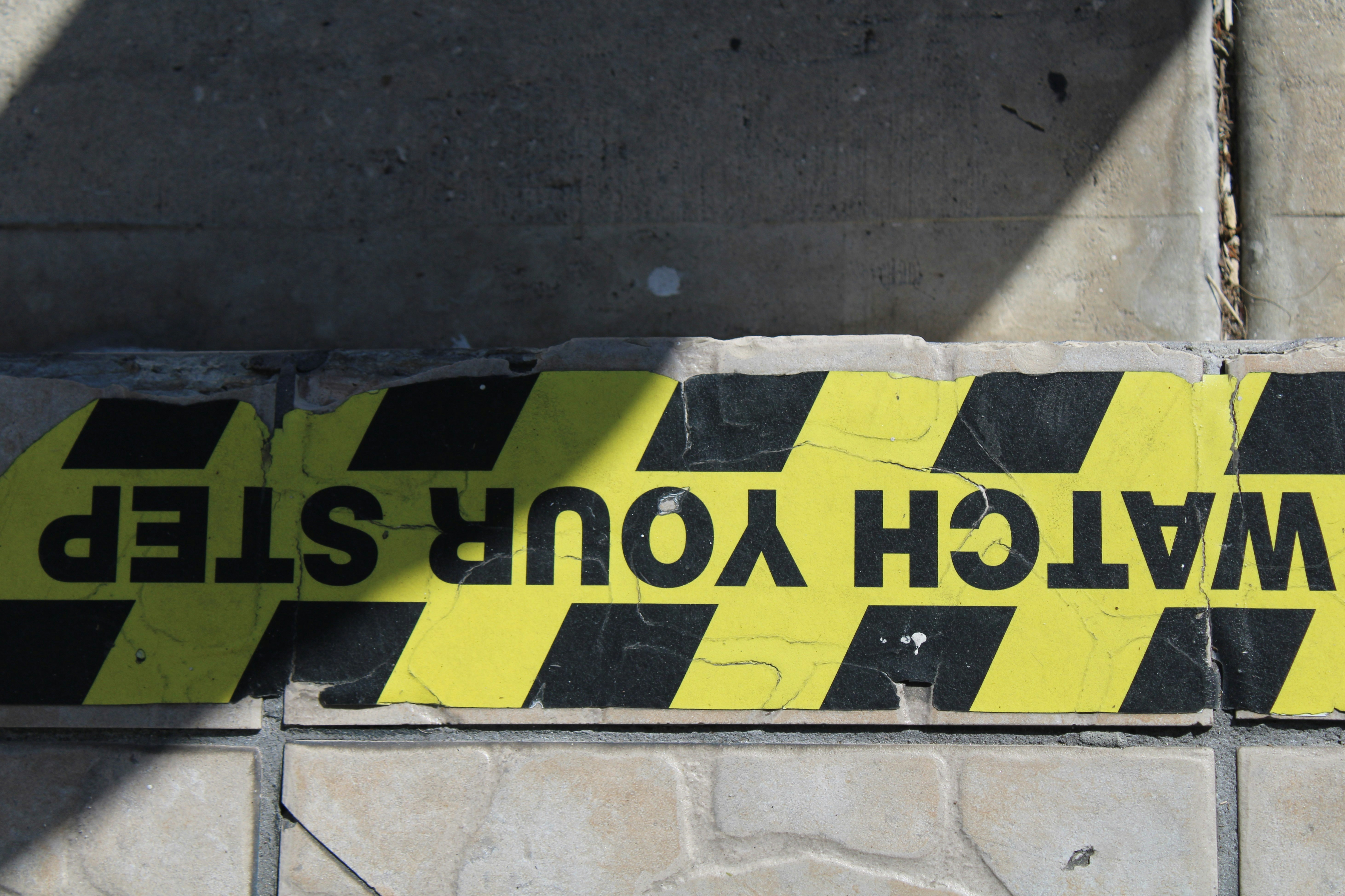 a yellow and black caution sign on a brick wall