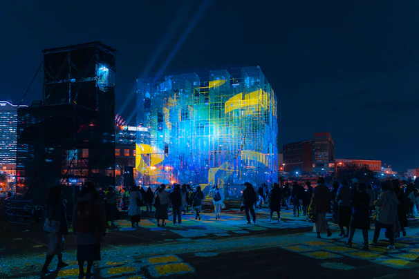 Evening view of the exhibition venue with illuminated signage and attendees.