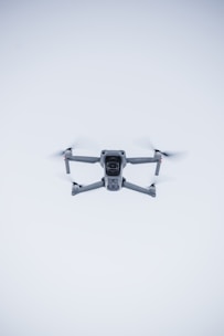 A sleek black drone hovering against a clean white background with red accents.