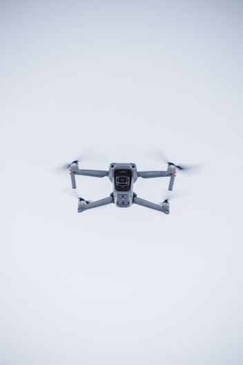 A sleek, minimalist 3D model of a drone hovering against a dark, moody background.