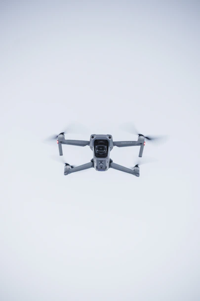 A sleek black drone hovering against a clean white background with red accents.