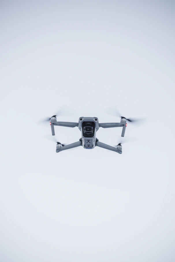 A sleek black drone hovering against a clean white background with red accents.