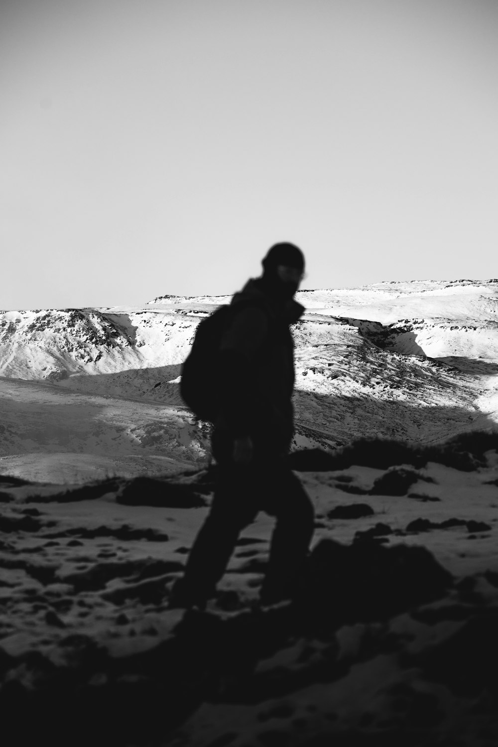 a black and white photo of a person walking in the snow