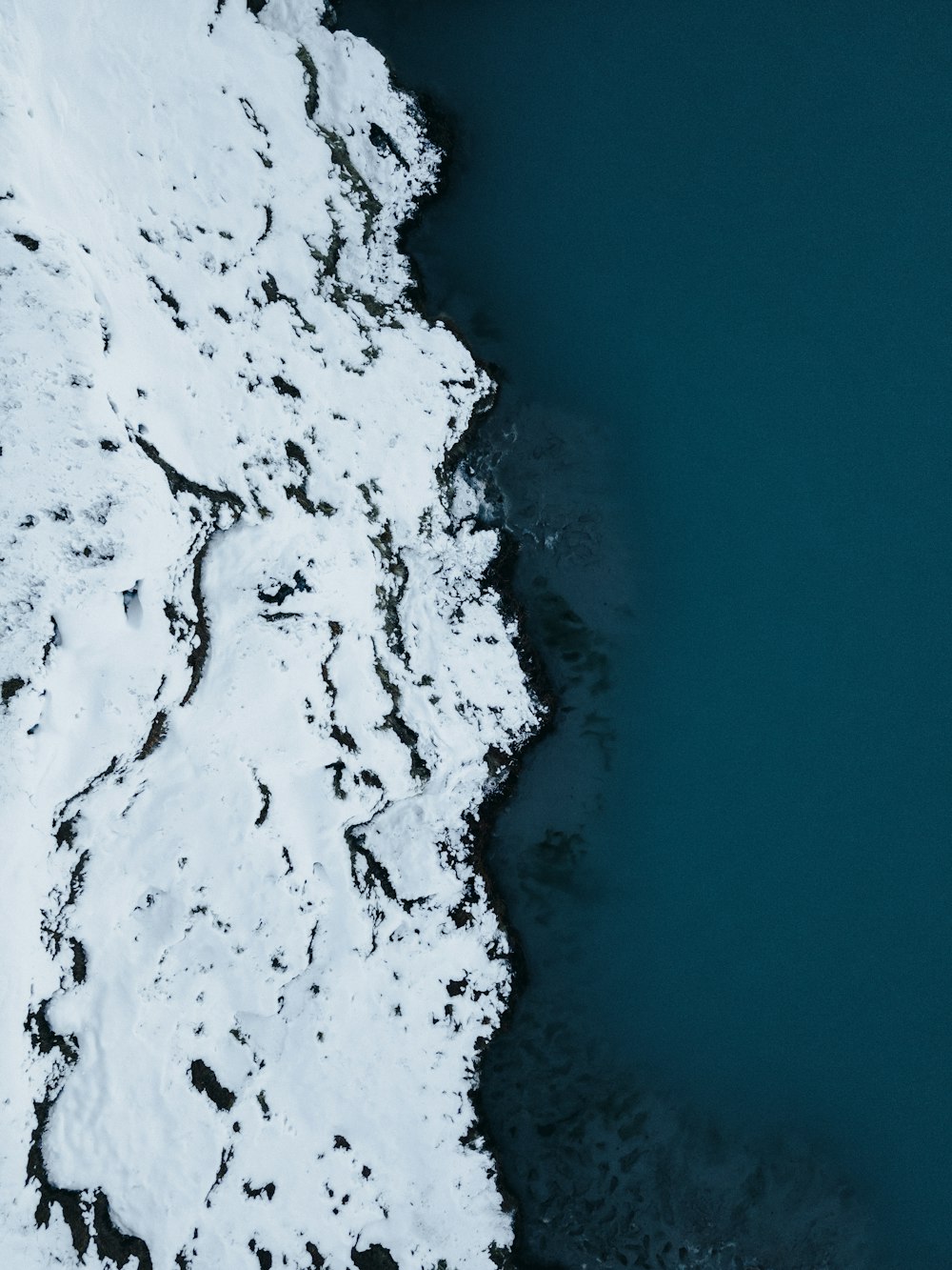 an aerial view of a body of water covered in snow