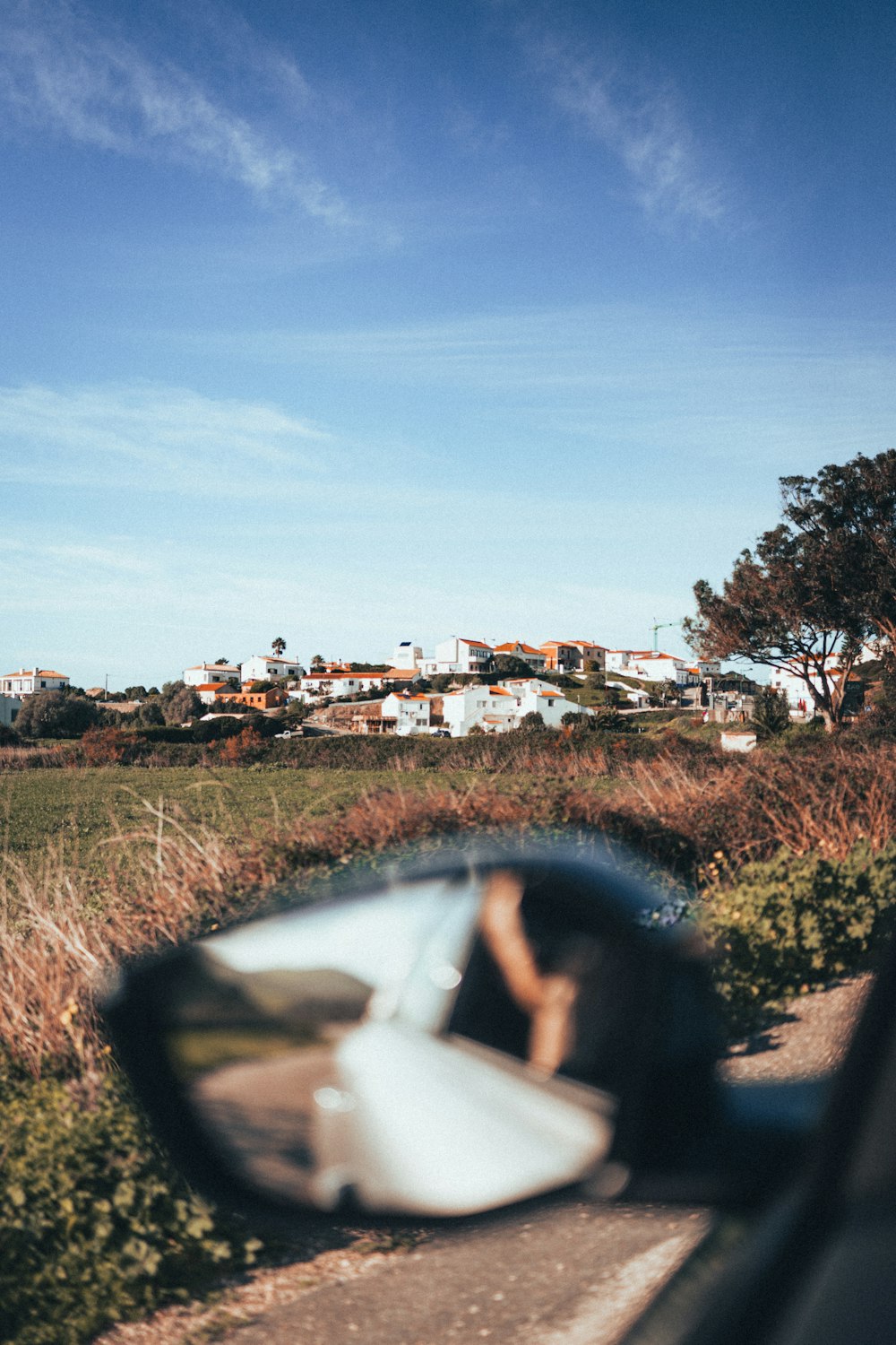 a car's side view mirror with a view of a town in the background