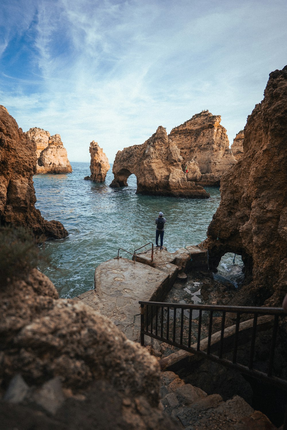 a person standing on a rock ledge near the ocean