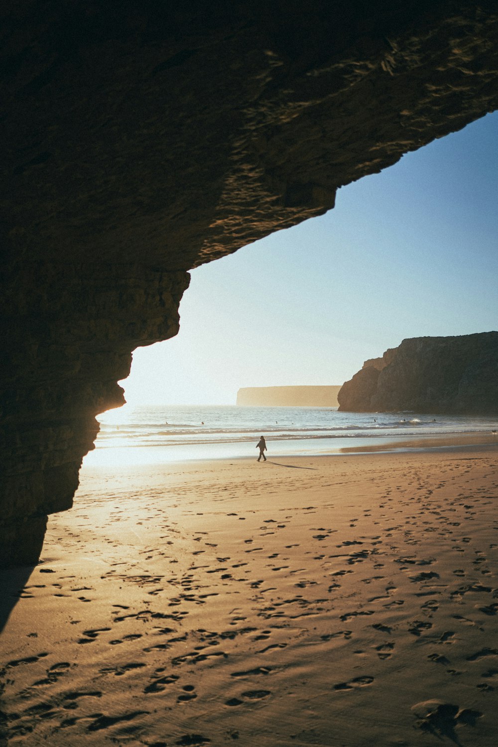 a person walking on a beach next to the ocean