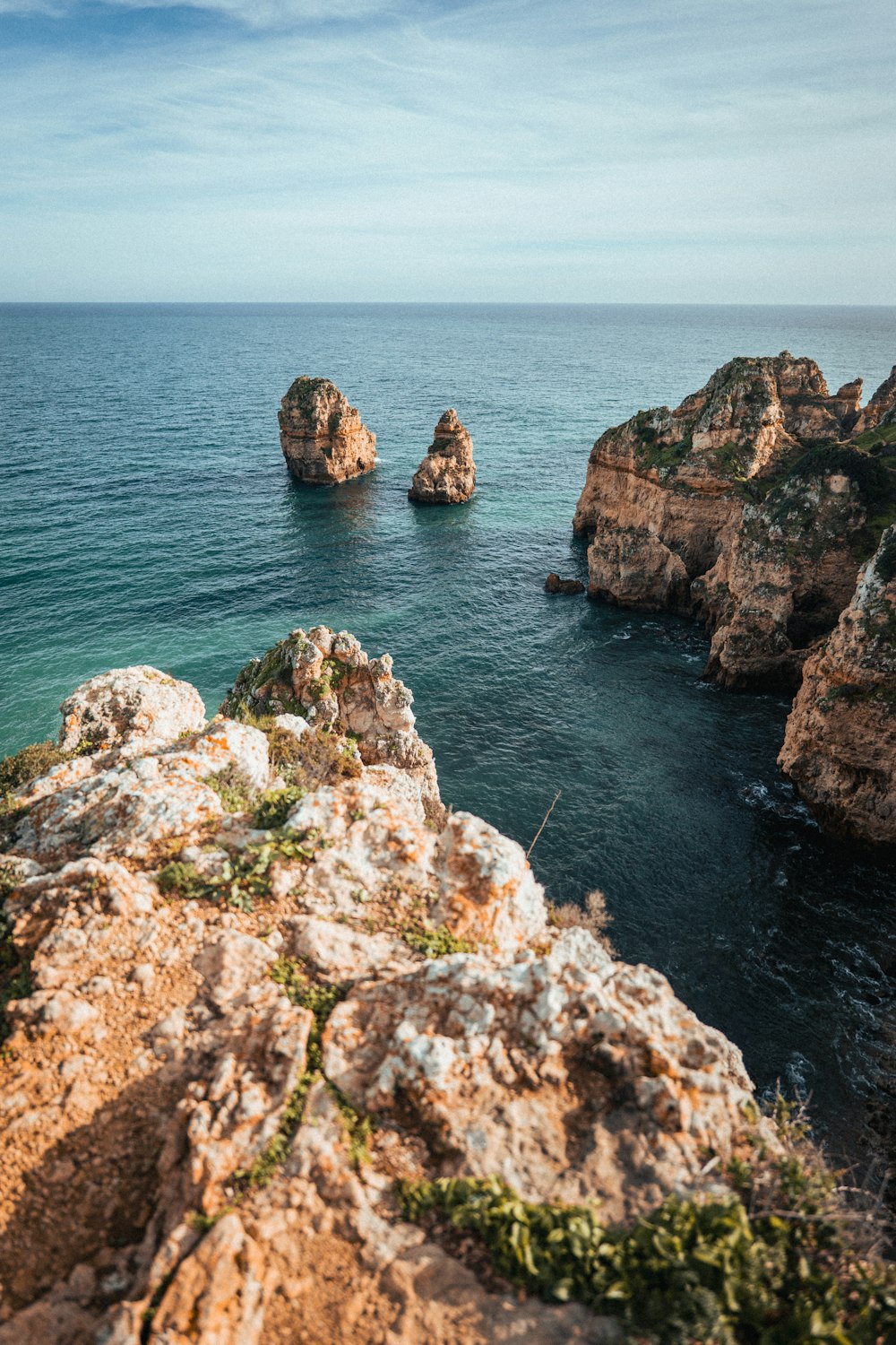 a couple of rocks sitting on top of a cliff next to the ocean