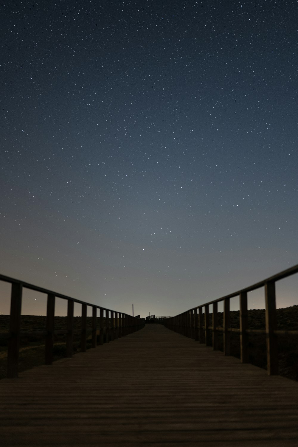 a wooden walkway with stars in the sky