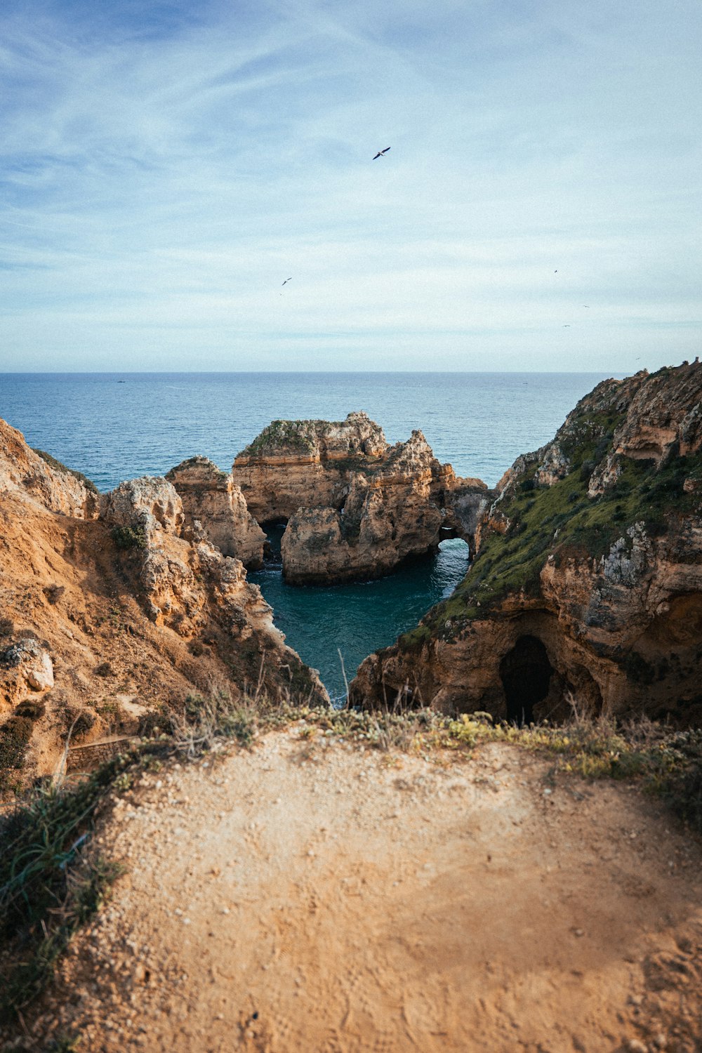 a dirt path leading to a cave on the ocean