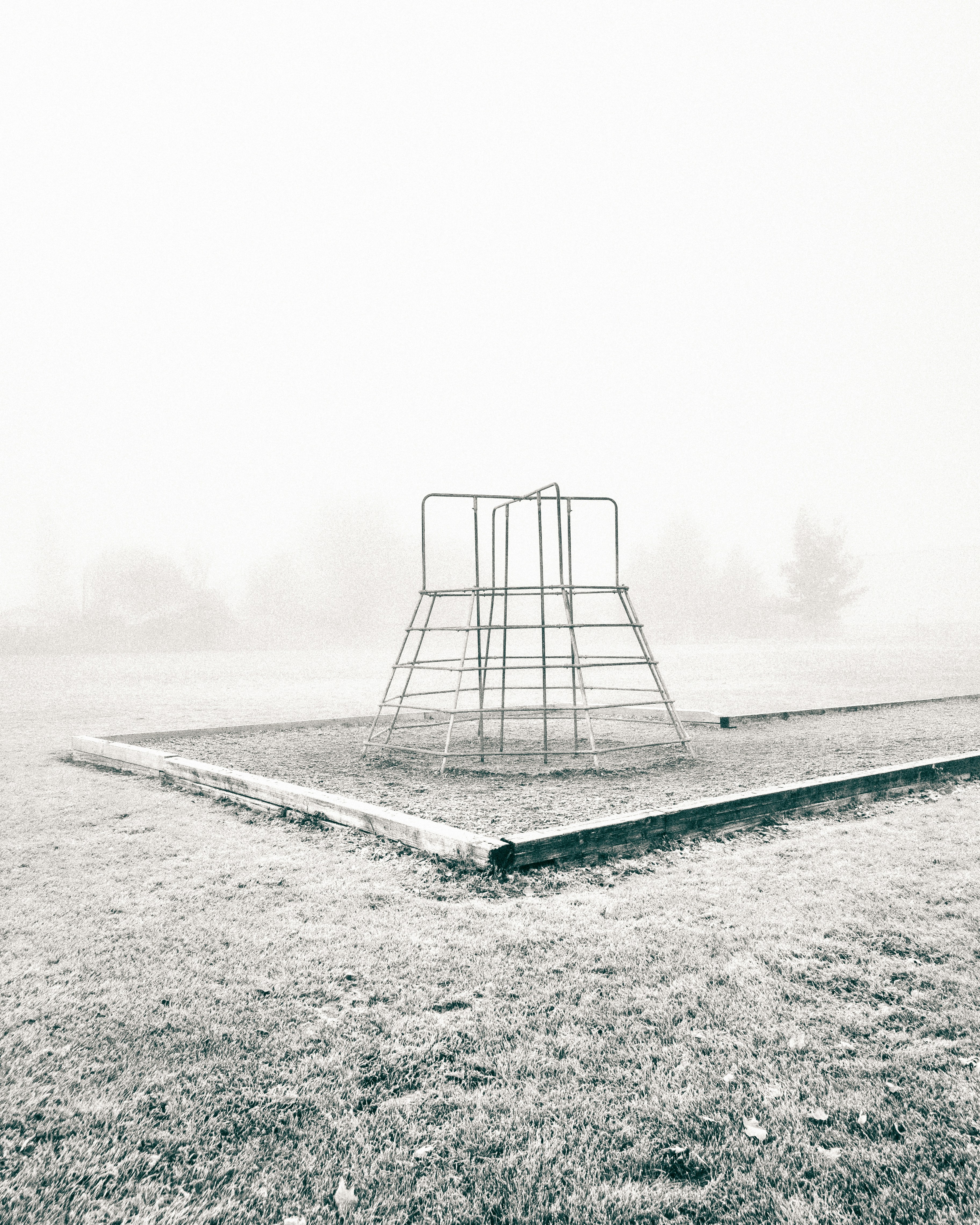 a black and white photo of a playground in the fog