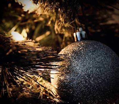 Close-up of sparkling glass ornaments hanging delicately on a pine branch.
