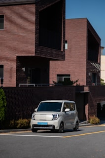 A compact white car parked in front of a charming Victoria neighborhood street
