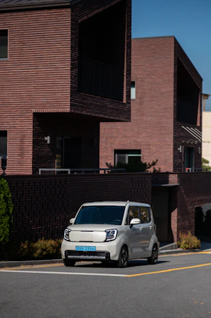 A compact white car parked in front of a modern house, clean and well-maintained.