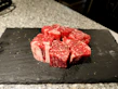 Fresh cuts of beef displayed on a black slate with Andes mountains in the background