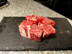 Fresh cuts of beef displayed on a black slate with Andes mountains in the background