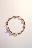 Close-up of delicate gold hoop earrings with tiny pearl accents on a soft fabric background