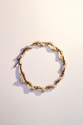 Close-up of delicate gold hoop earrings with tiny pearl accents on a soft fabric background