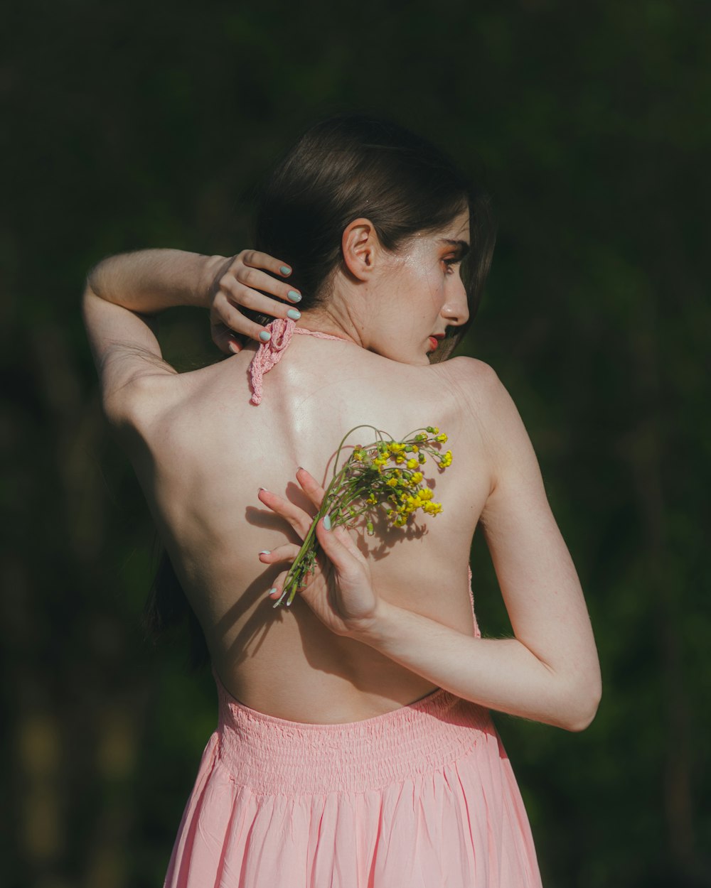 a woman in a pink dress holding a flower