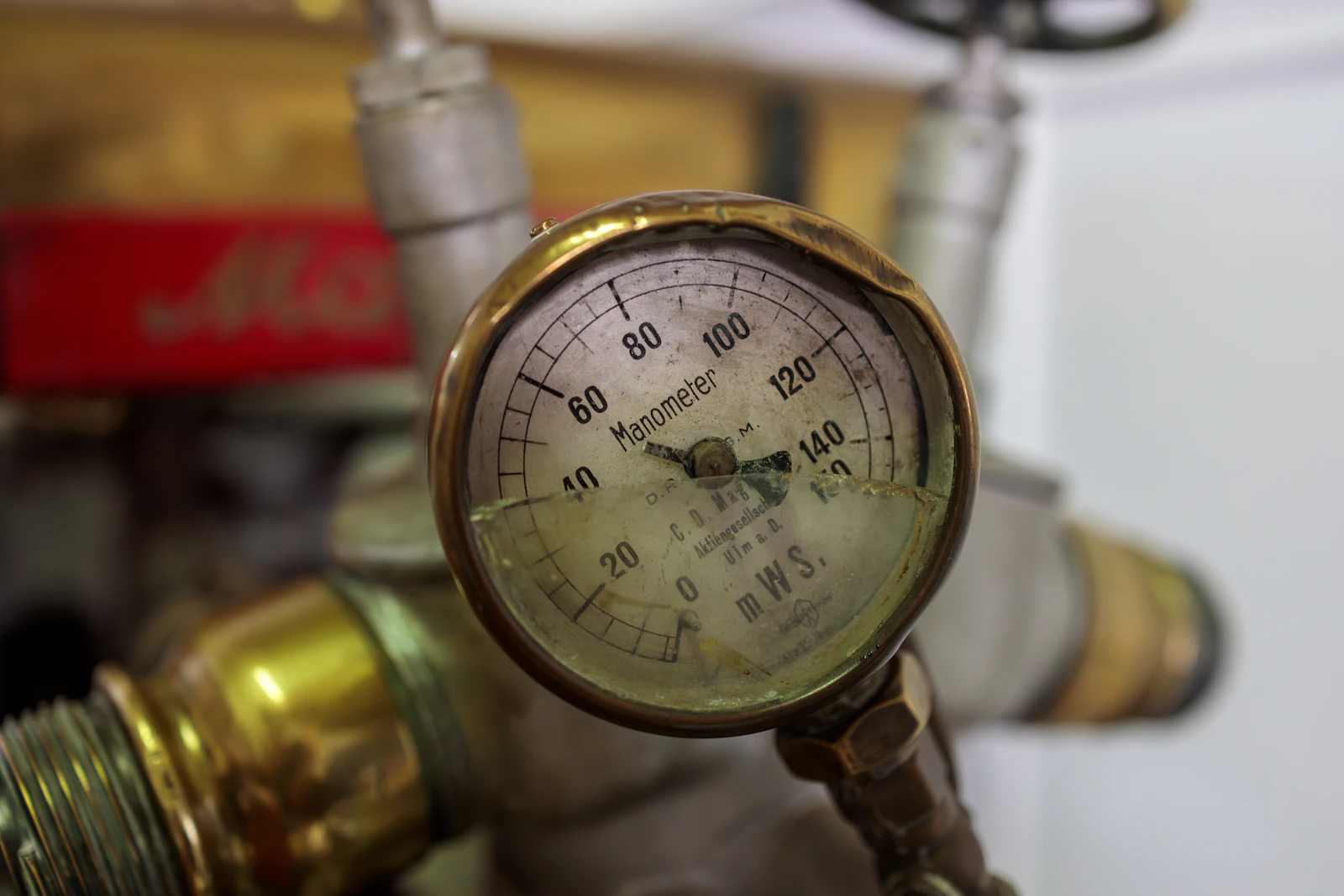 A close-up of a vintage analogue pressure gauge dial attached to a pipe