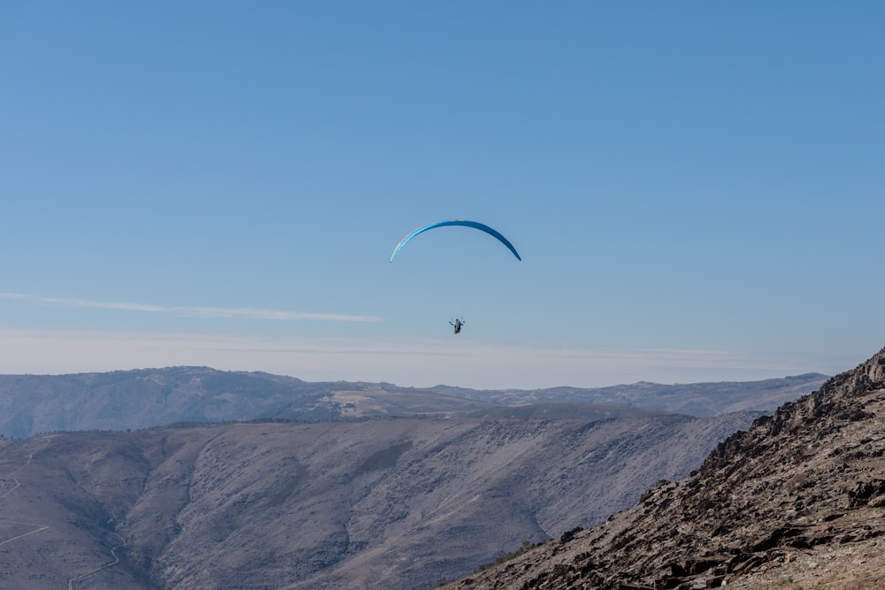 a paraglider is flying over a mountain range